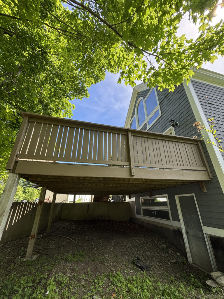 Underside and support posts of refinished elevated deck in Pepperell MA by Cramb Painting Co.
