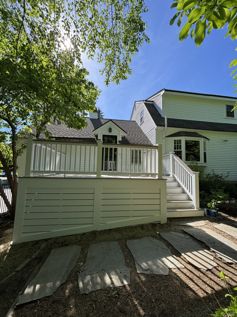 Sunlit elevated deck refinished by Cramb Paint Co. in Hopkinton MA with white railings and privacy skirting
